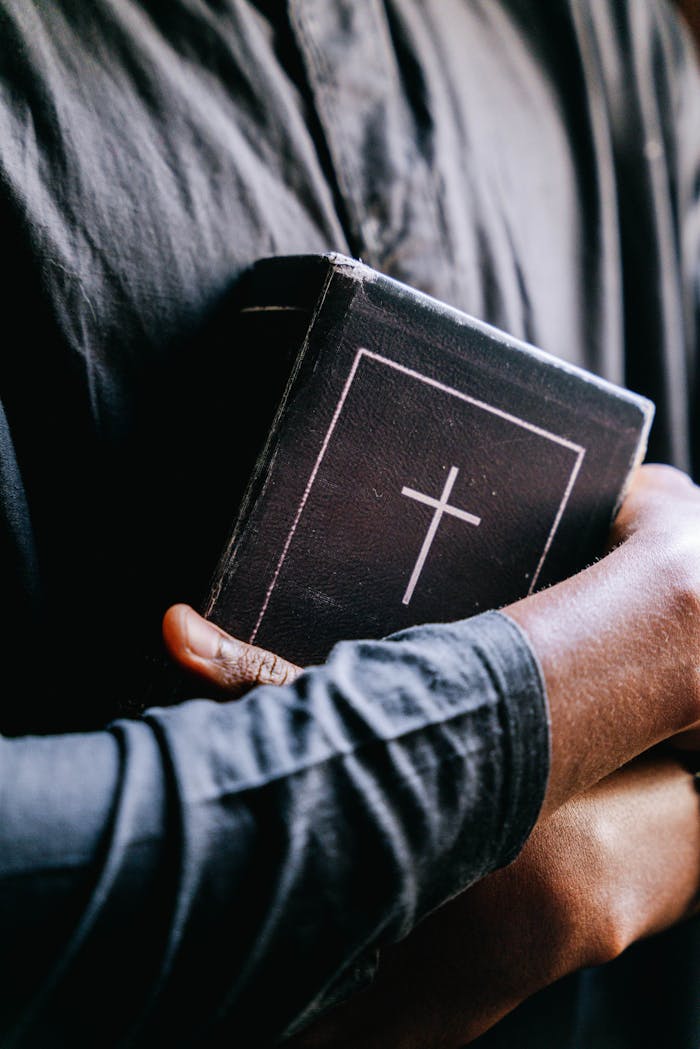 services-03 Close-up of a person holding a holy bible with a cross, focusing on religion and faith.